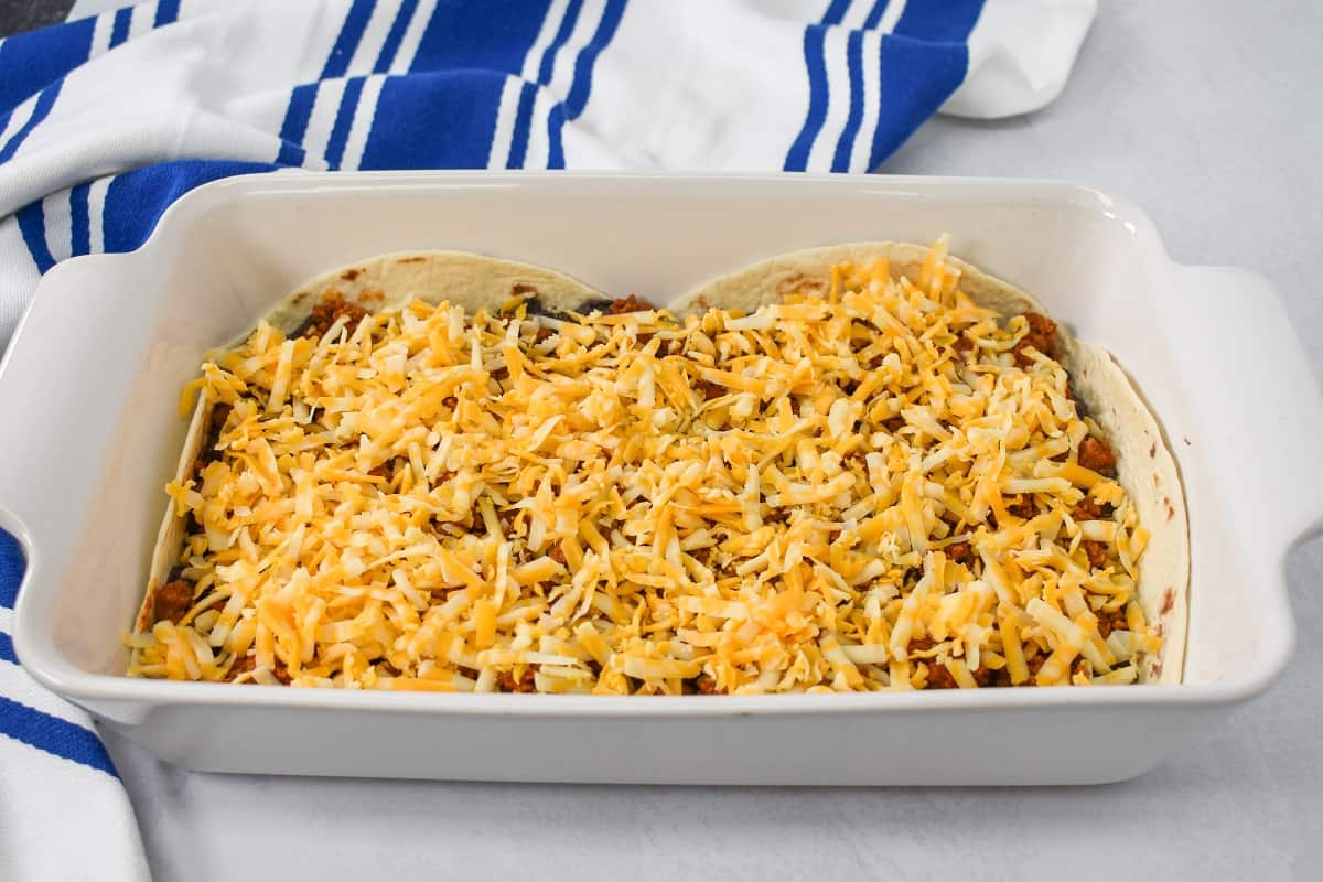 A layer of shredded cheese added to the top of the ingredients in the baking dish.