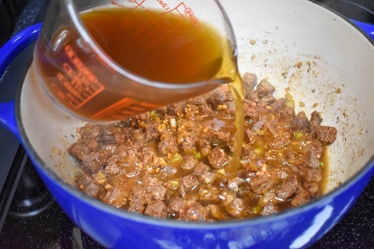 Beef broth being added to the ingredients in the pot.