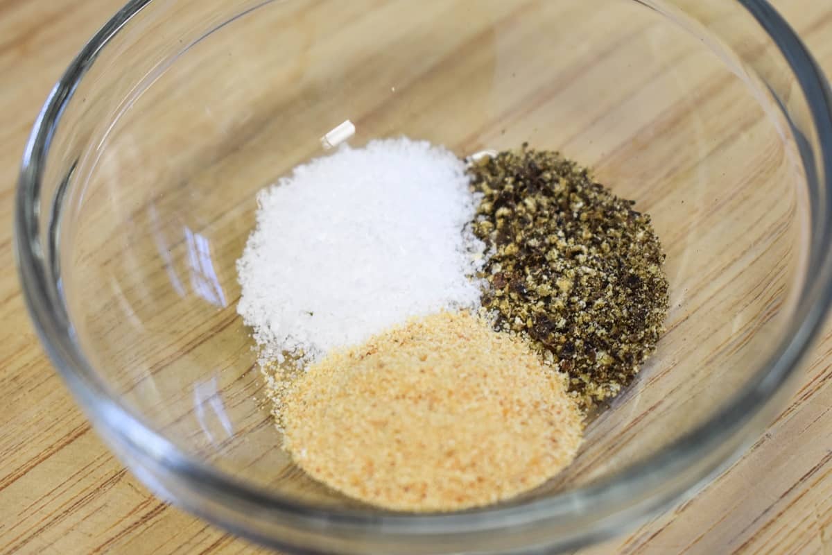Salt, garlic powder, and black pepper in a small glass bowl.