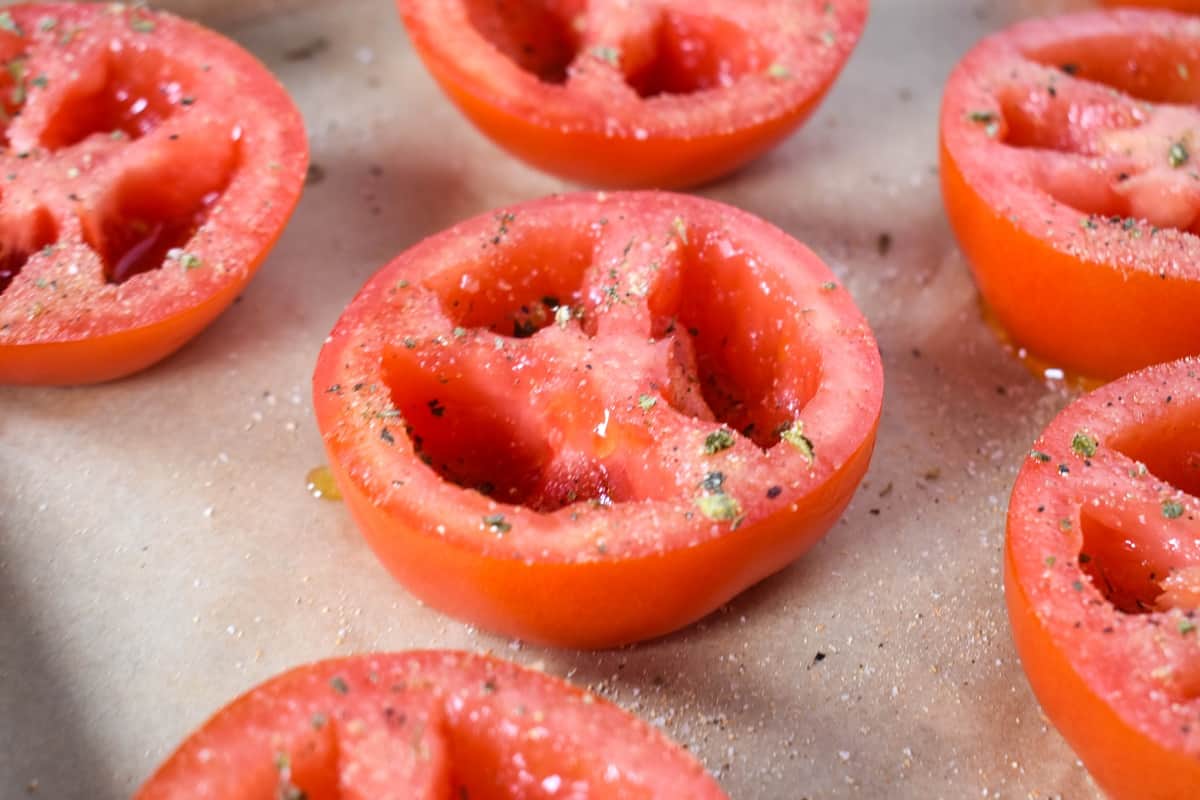 Scooped tomato halves sprinkled with seasoning.