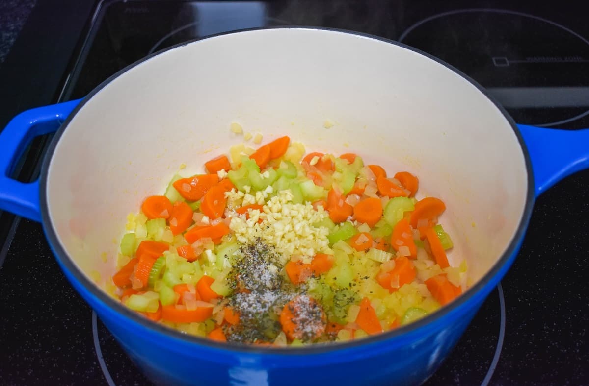 Minced garlic and spices added to the onions, carrots, and celery in the pot.