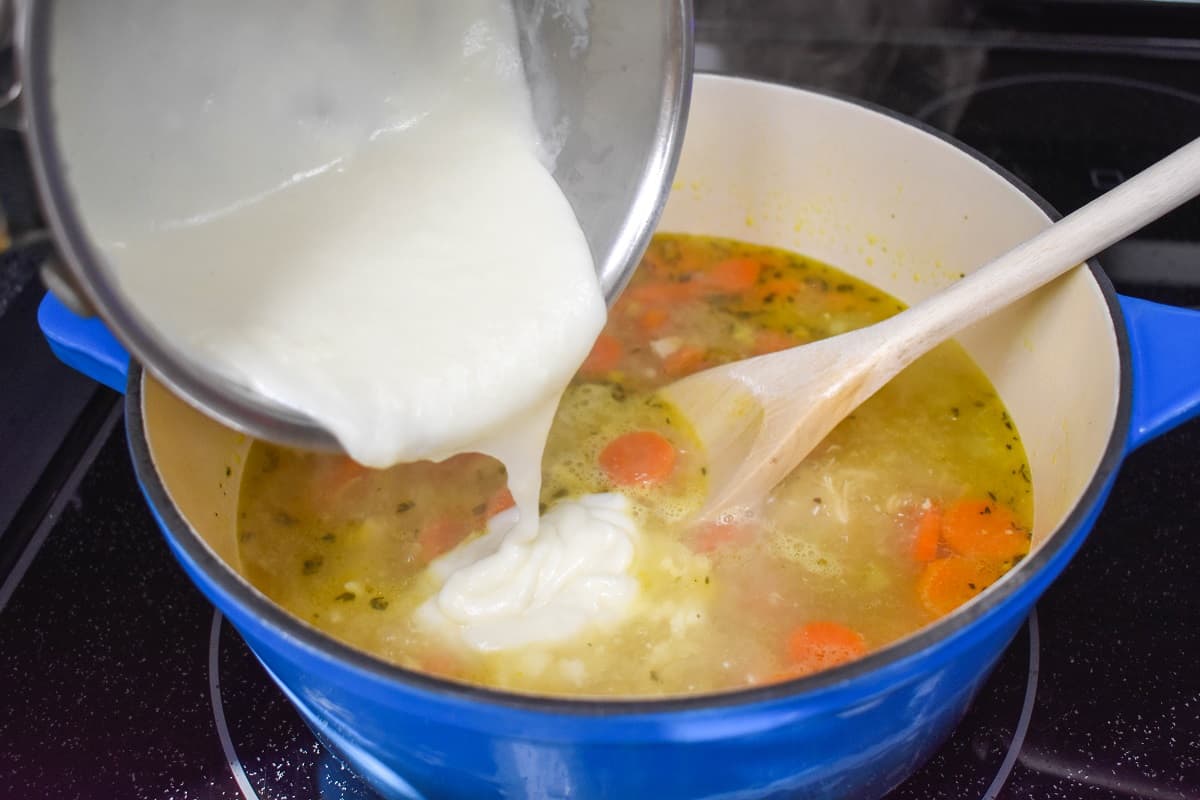 The white sauce being added to the soup.
