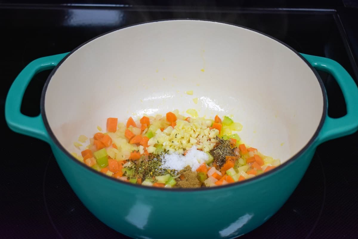 Garlic and spices added to the onions, carrots, and celery in the pot.