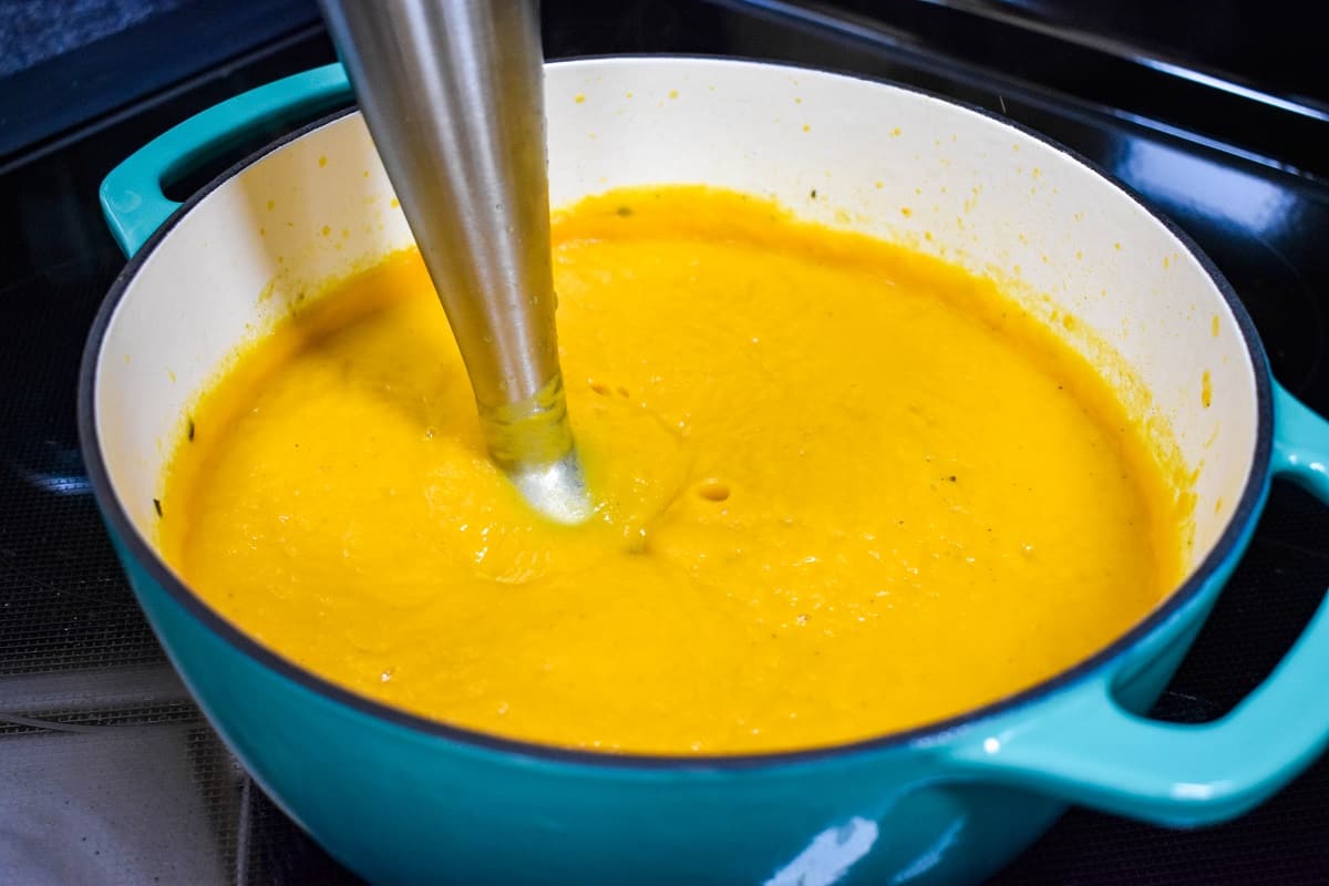 The processed soup in the pot with an immersion blender.