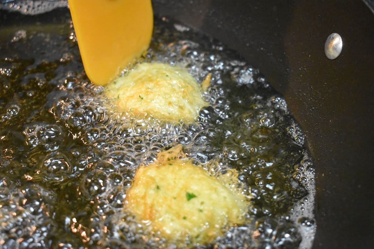 Two fritters frying in oil.