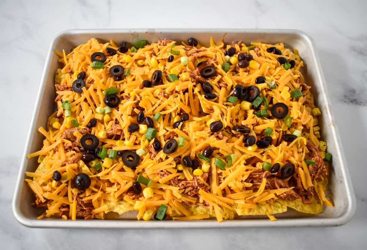 Black olive, green onions, and corn sprinkled over the chicken nachos.