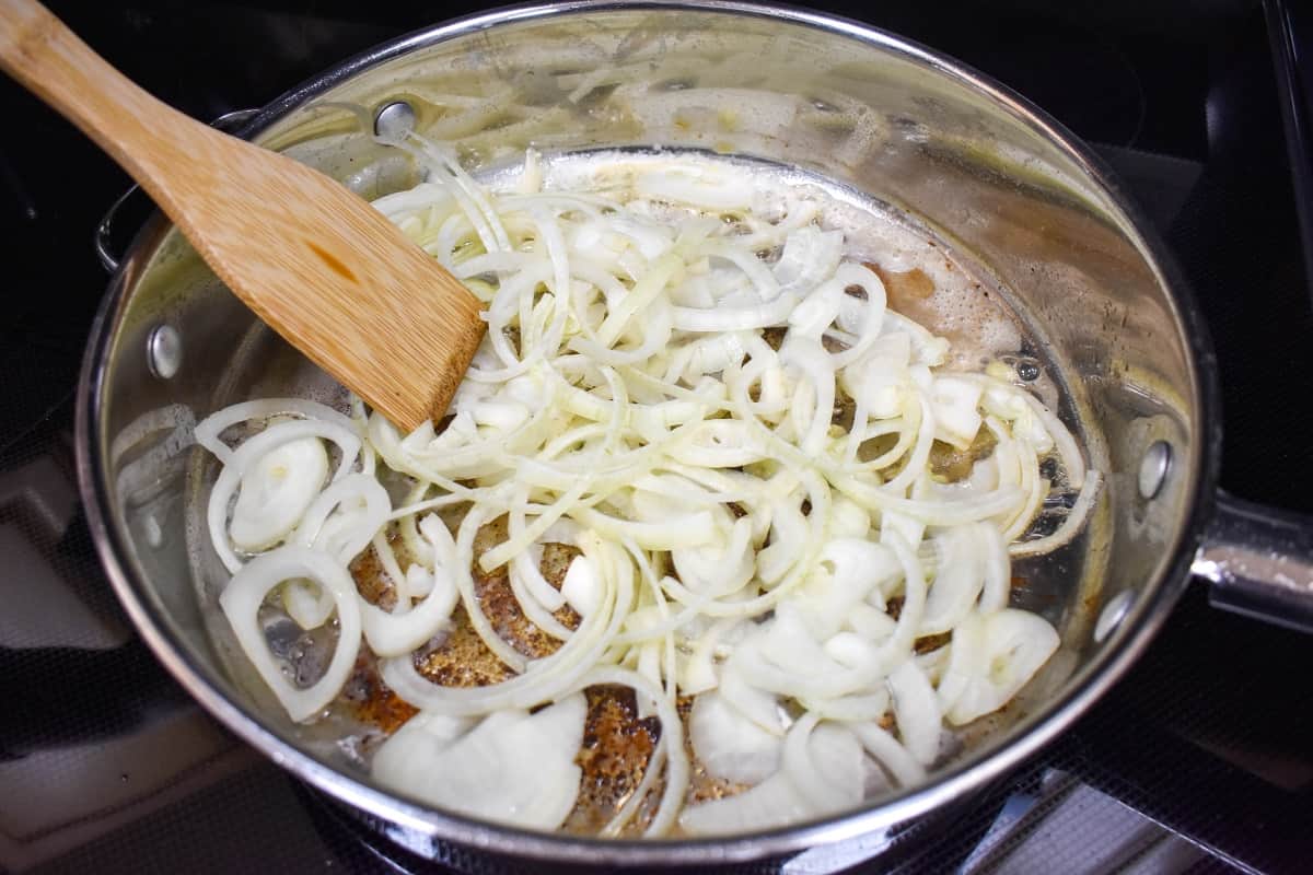 Sliced onions sautéing in a large skillet.