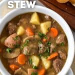 The stew served in a white bowl with sliced bread on the side.