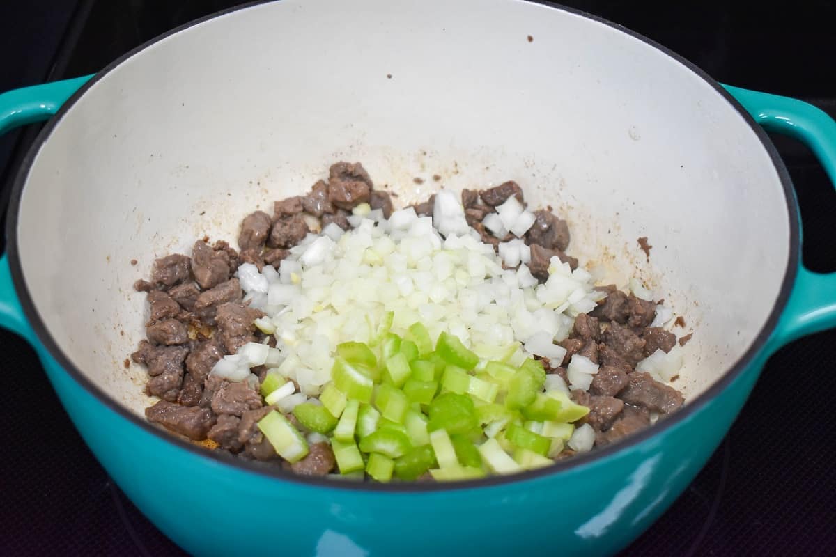 Diced onions and celery added to the browned beef in the pot.