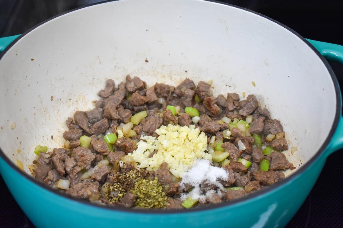 Minced garlic and seasoning added to the beef, onion, and celery mixture in the pot.