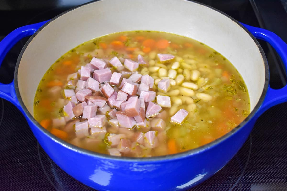 Diced ham and white beans in the pot with the broth and other ingredients.