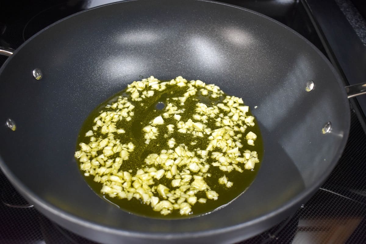 Minced garlic sautéing in olive oil in a large, non-stick skillet.