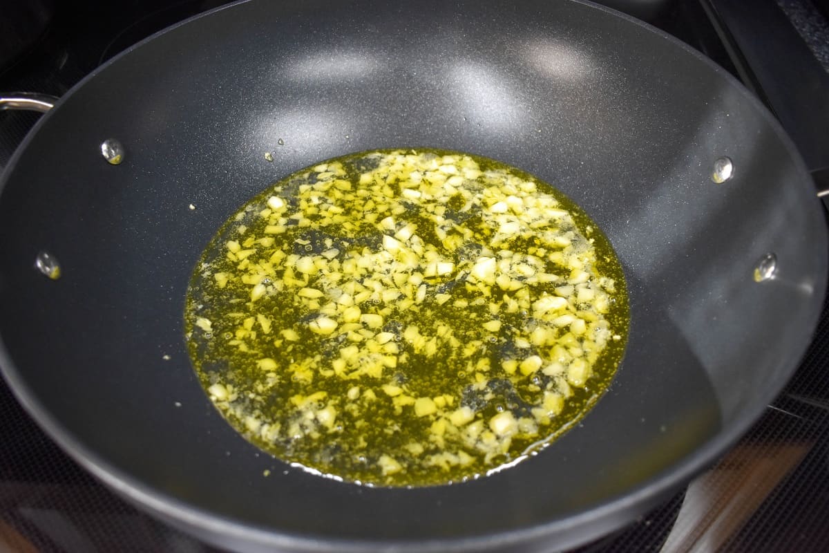 Garlic in olive oil and white wine sautéing in a large, non-stick skillet.