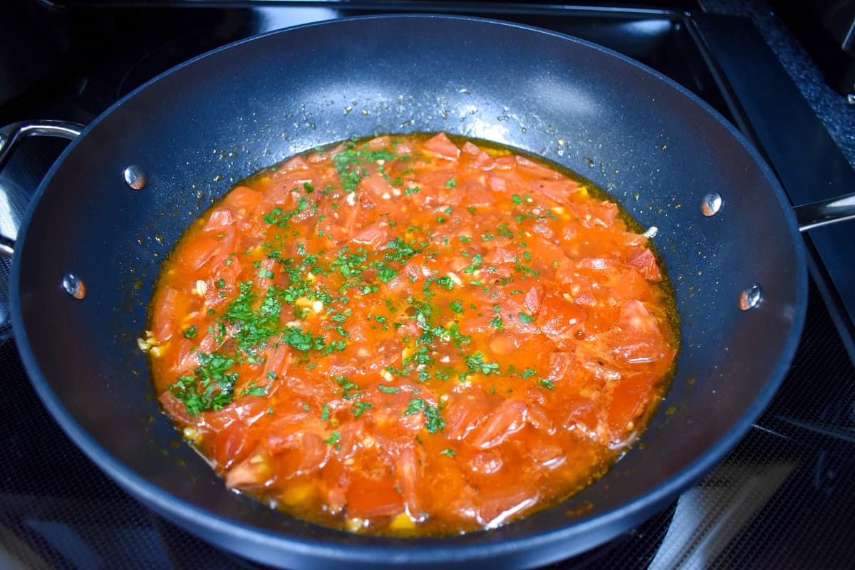 The tomatoes in the skillet after cooking with chopped parsley added.