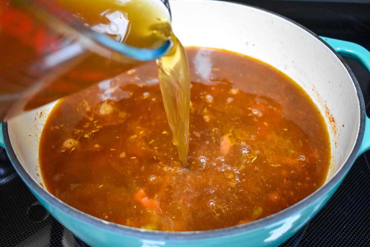 Beef broth being added to the soup.