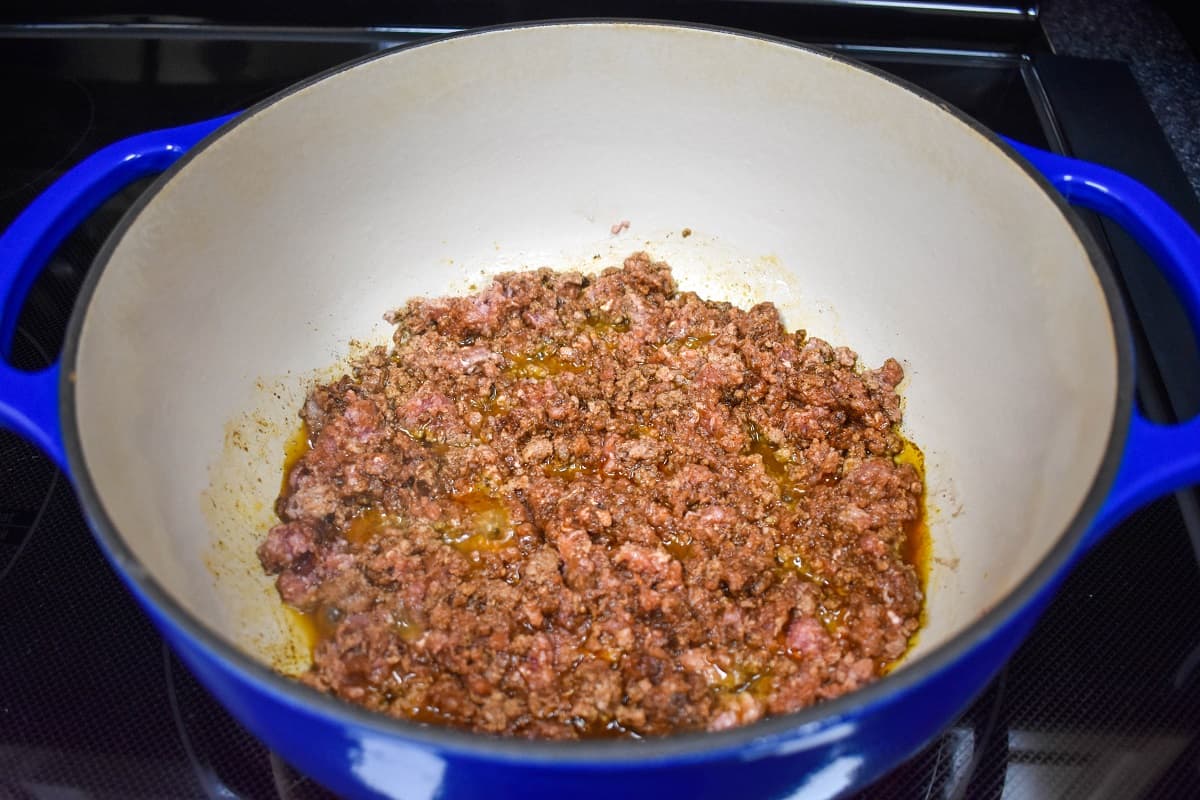 Seasoned ground beef browning in a large white and blue pot.
