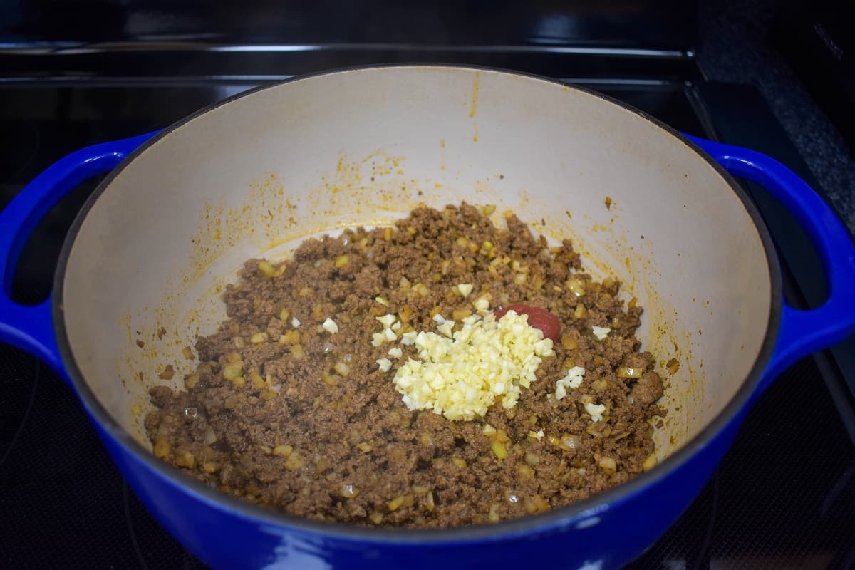 Minced garlic and tomato paste added to the beef and onions in a large pot.