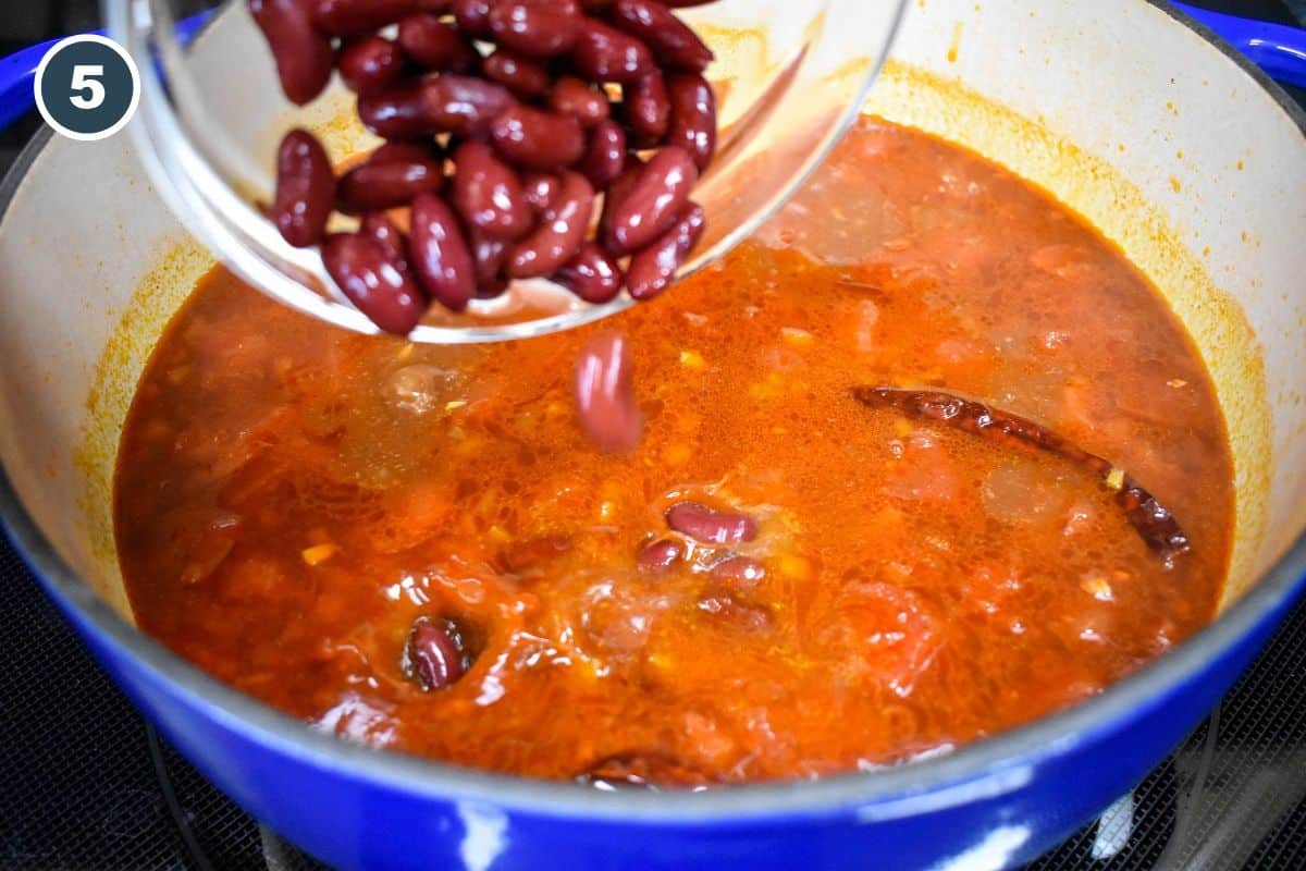 Red kidney beans being added to the simmering chili mixture.