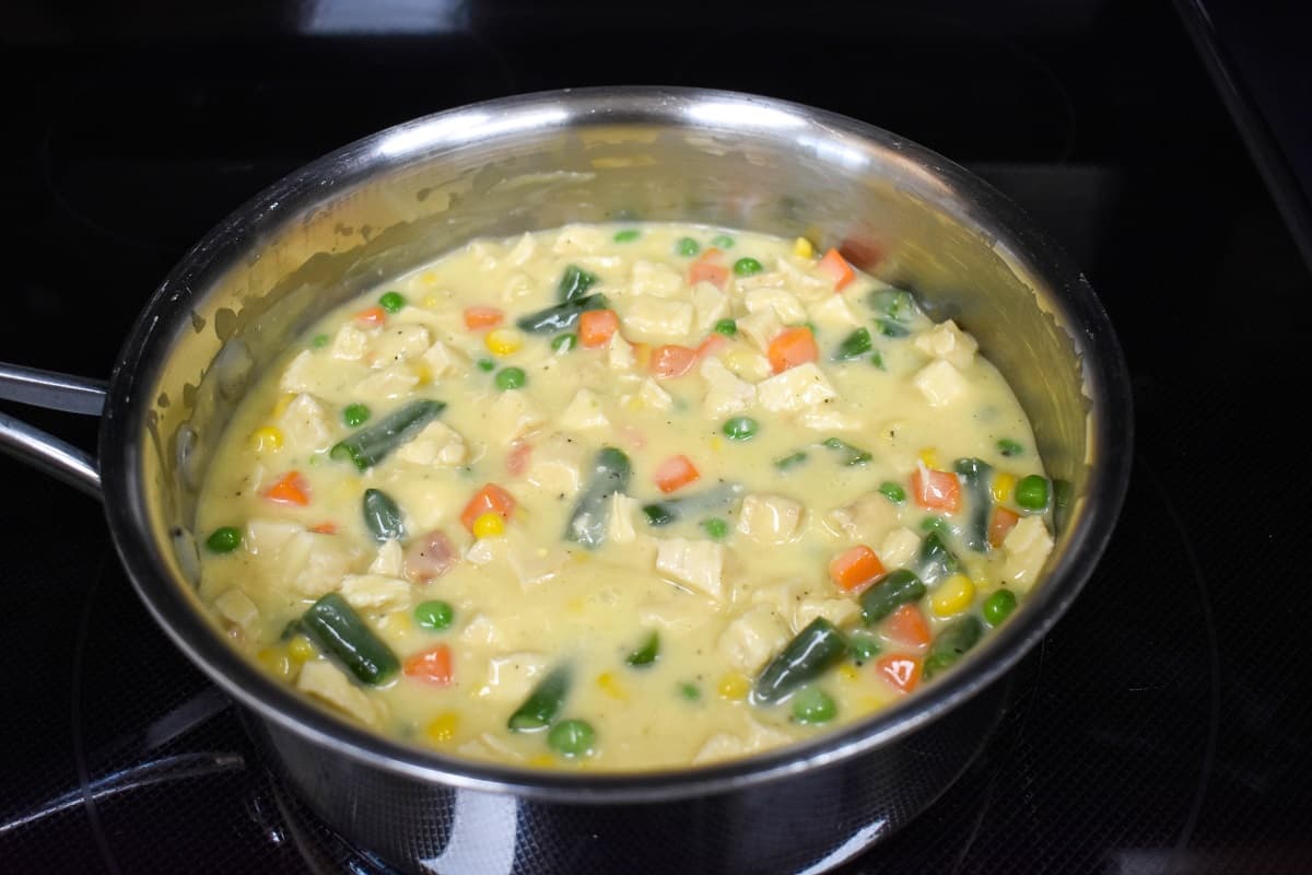 The chicken, cream of chicken soup, broth, and vegetables combined in a saucepan.