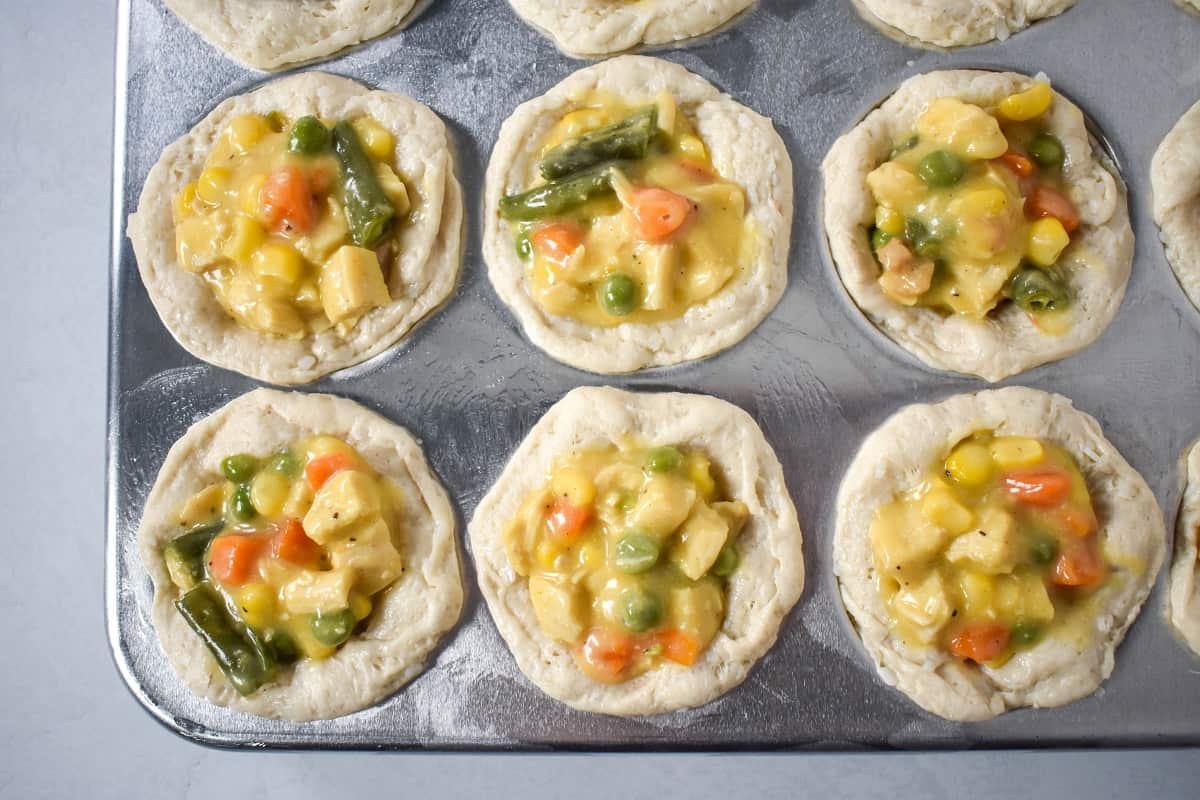 Biscuits filled with the chicken mixture in a muffin pan.