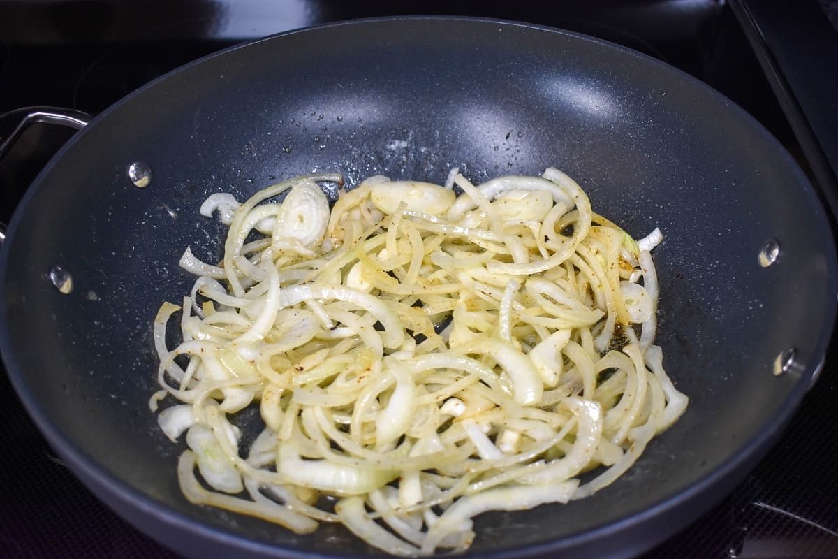 Sliced onions added to a large, non-stick skillet.