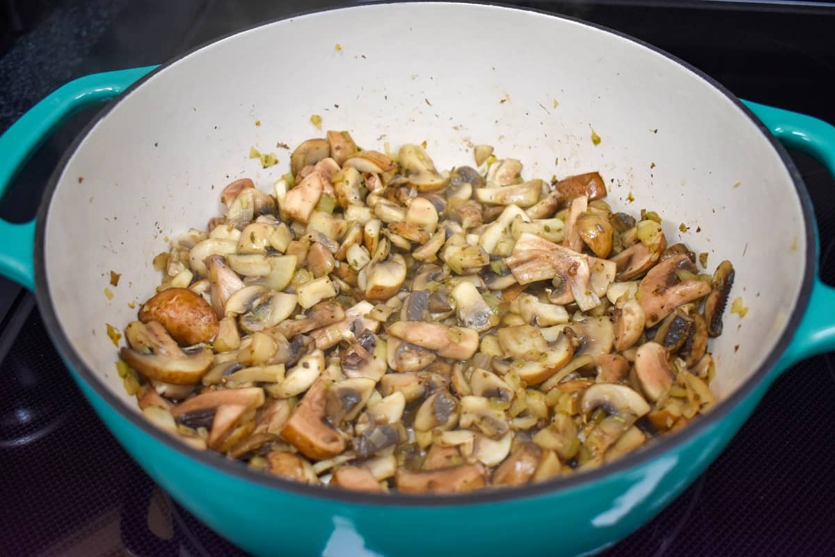 The sautéed onions, garlic, spices and mushrooms in an aqua and white pot.