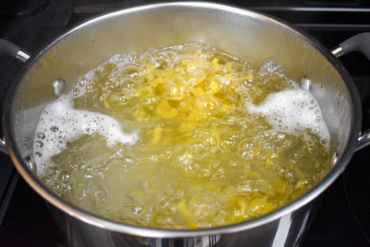 Macaroni cooking in boiling water in a large pot.