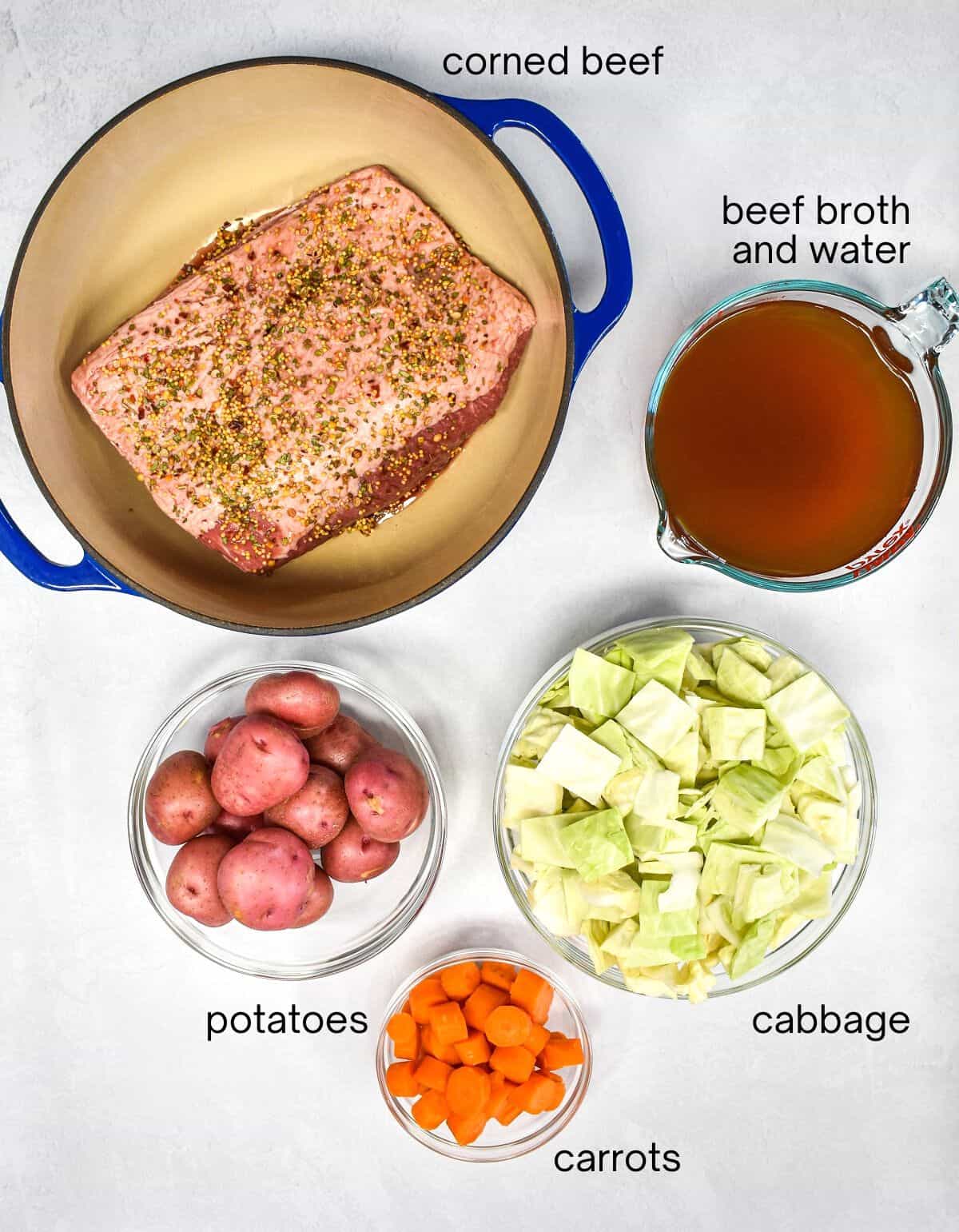 The ingredients for the dish arranged on a white table, each labeled with the name in small black letters.