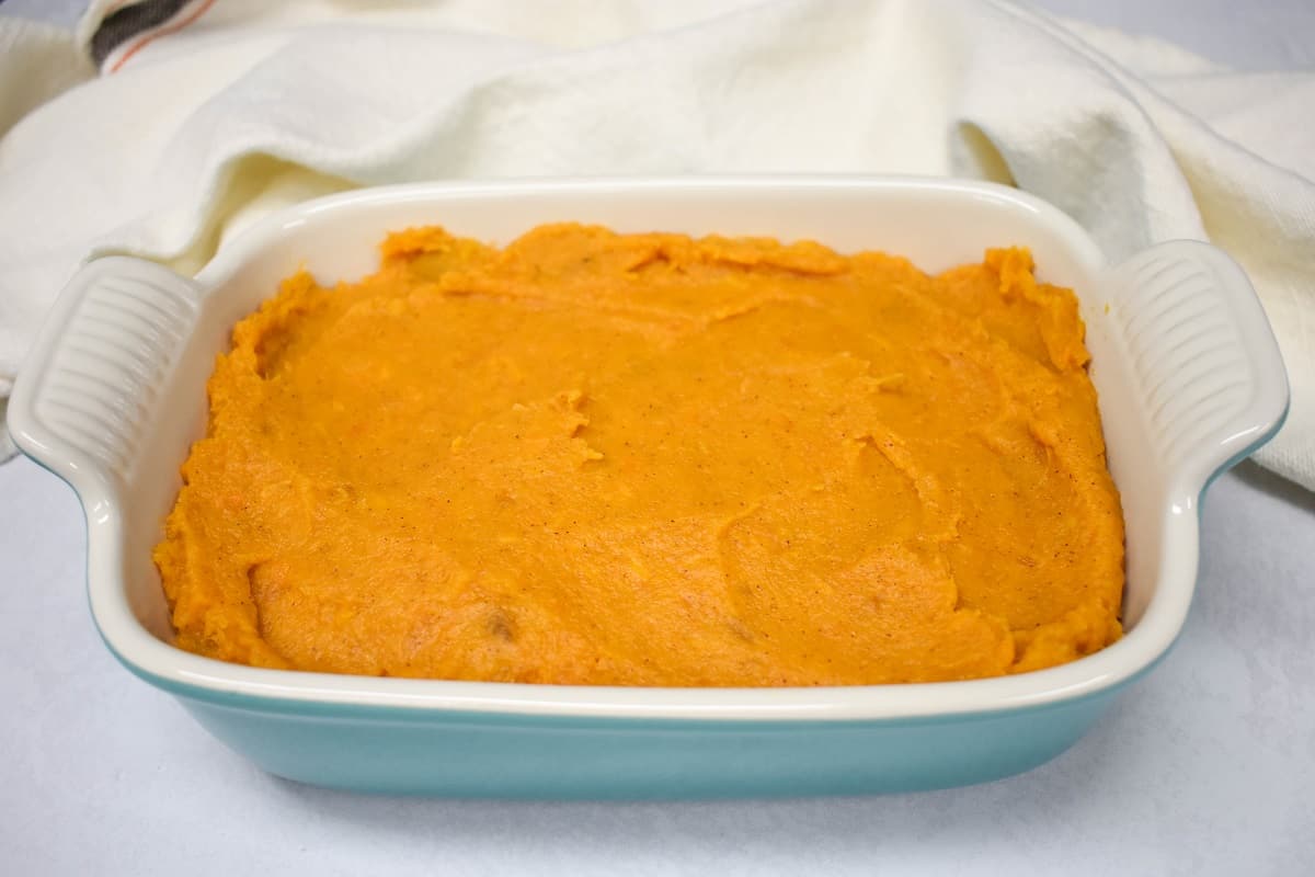 The mixture in a white and teal baking dish with the top smoothed out.