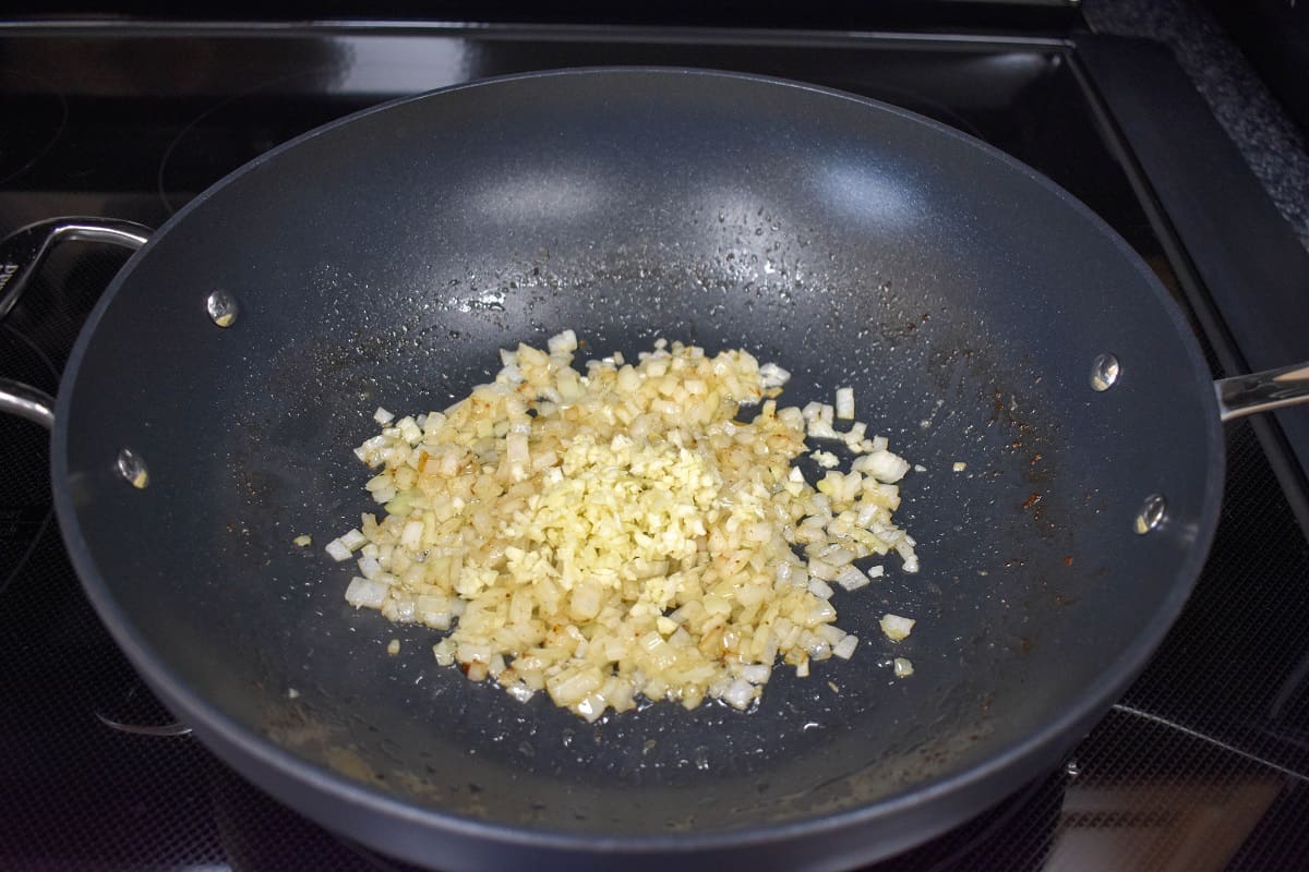 Minced garlic added to onions sautéing in a large, non-stick skillet.
