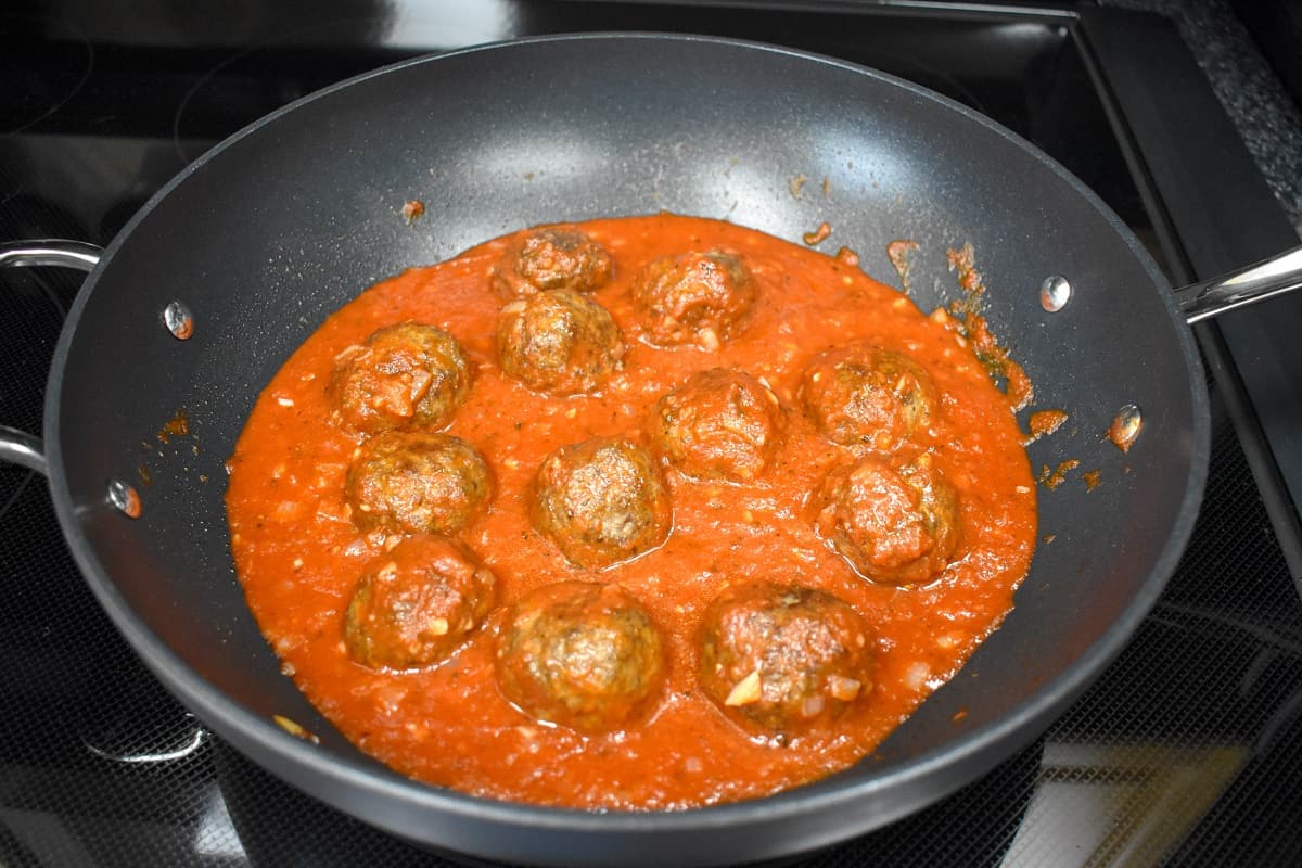 Meatballs in red sauce in a large, non-stick skillet.