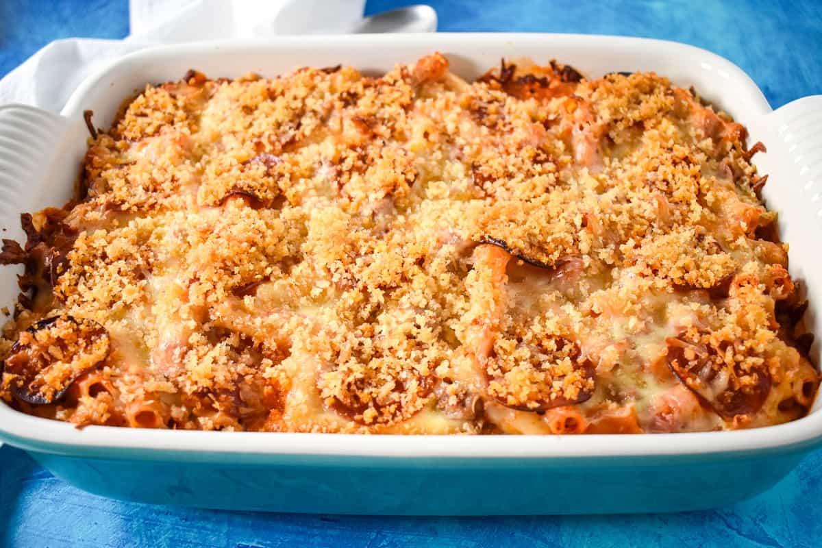 The finished pizza pasta bake in a large casserole dish set on a blue table.