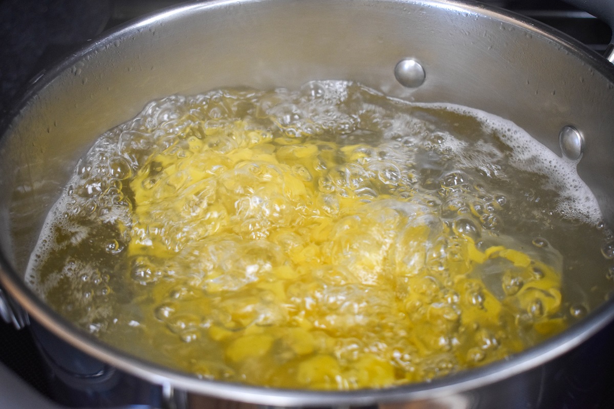 Elbow macaroni cooking in a large pot filled with water.