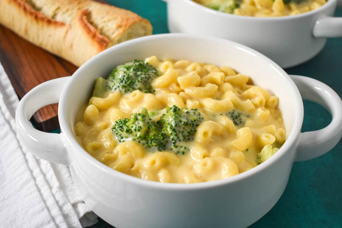 A close up of the finished macaroni and cheese served in a white bowl with bread in the background.