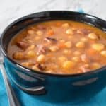 The chickpea soup served in a black bowl.