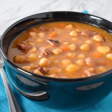 The chickpea soup served in a black bowl.