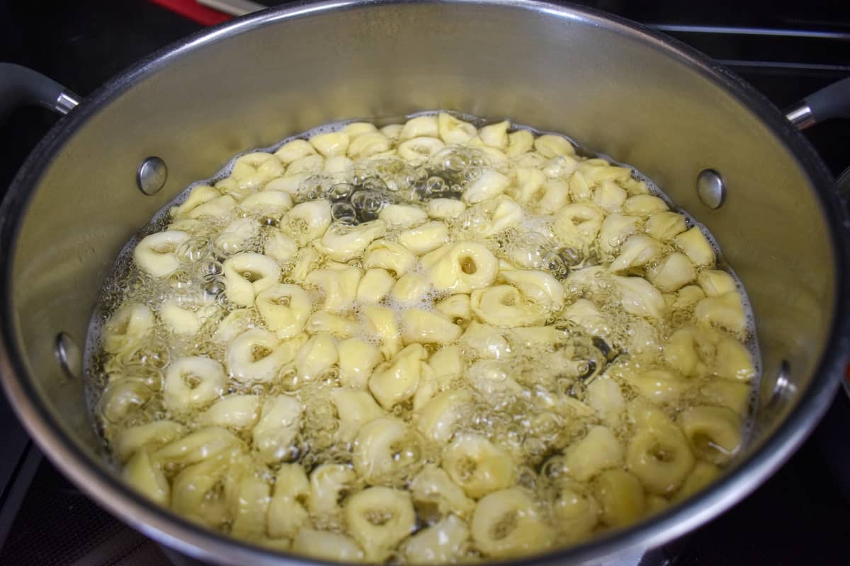 Tortellini cooking in boiling water in a large stockpot.