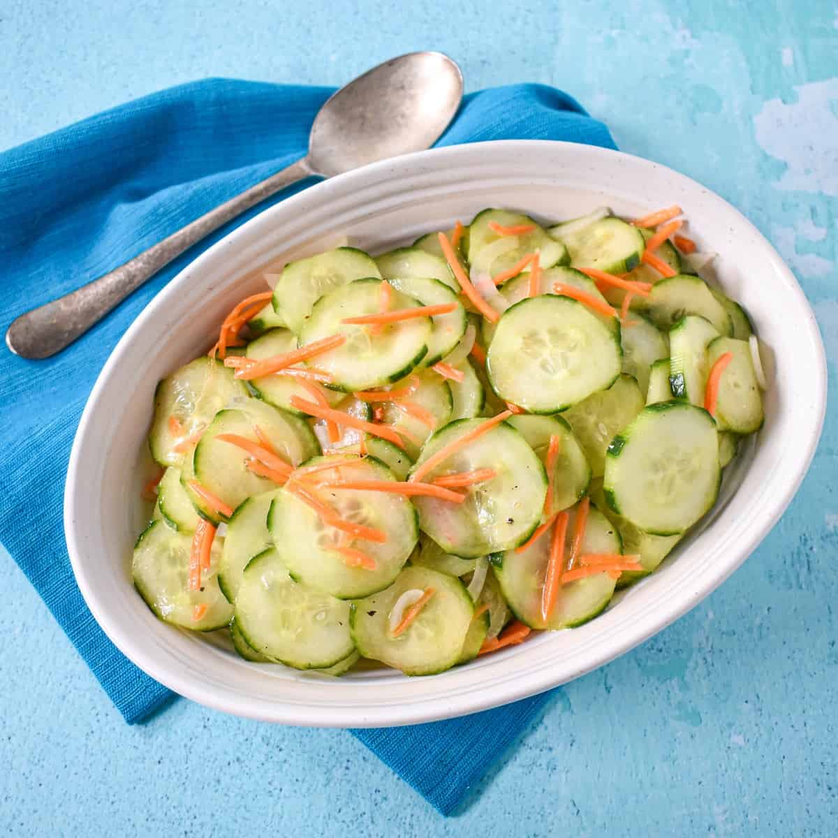 The finished side dish served in a white bowl and set on a light blue table with a teal linen and serving spoon.