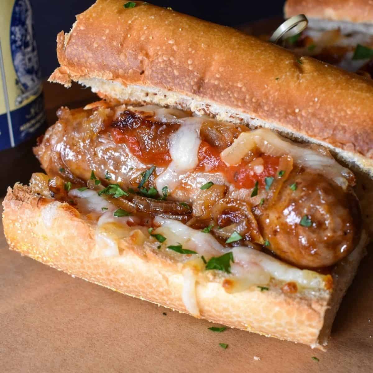 A close up image of an Italian sausage sandwich, served on a wood cutting board lined with brown parchment paper.