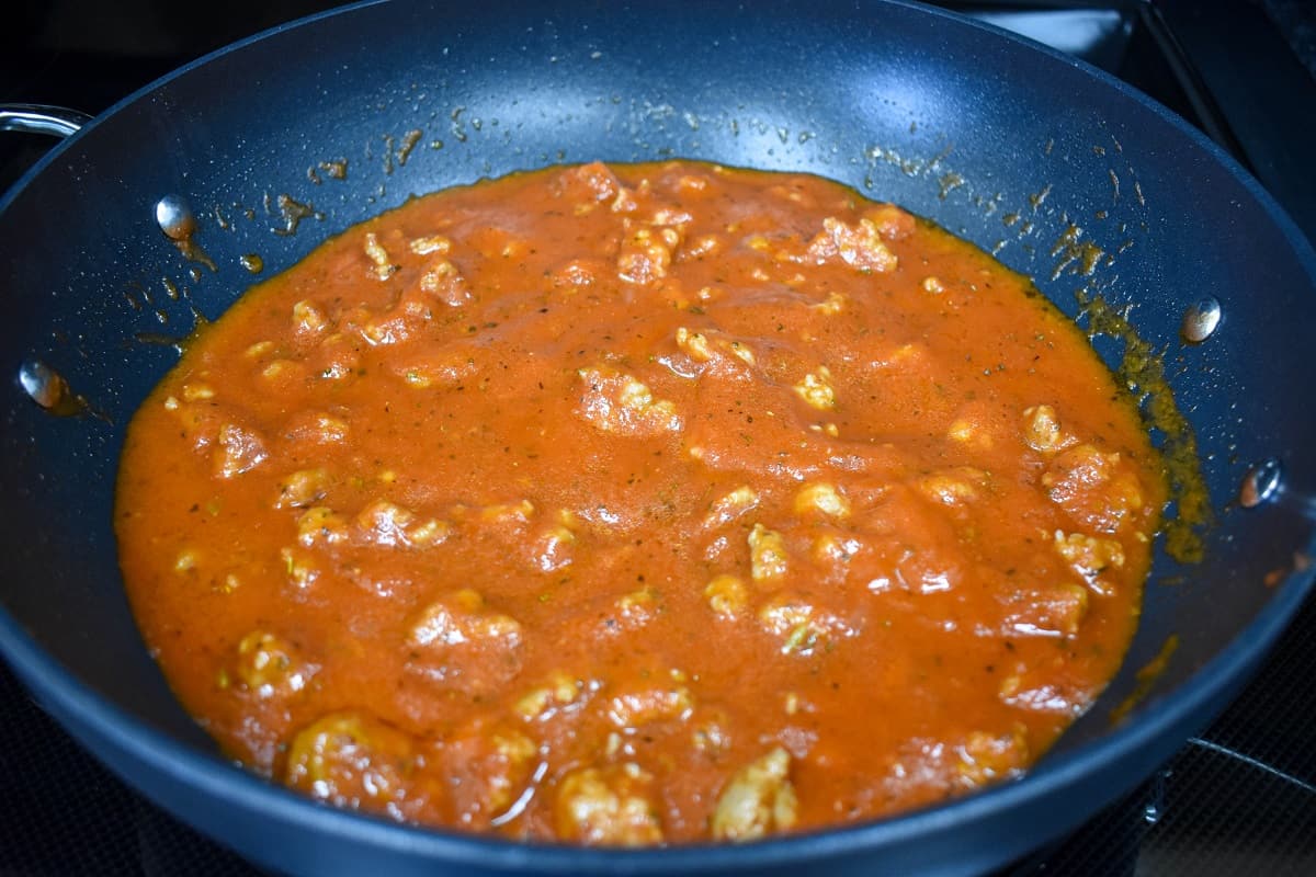 The sausage pasta sauce cooking in a large, black skillet.