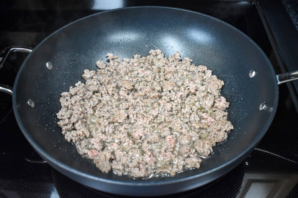 Browned ground beef in a large, black skillet.
