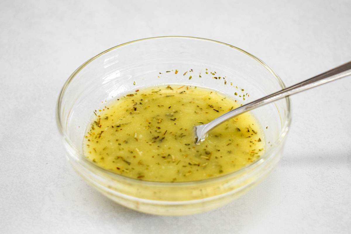 Butter, oil, and seasoning mixed in a small glass bowl, with a small fork.