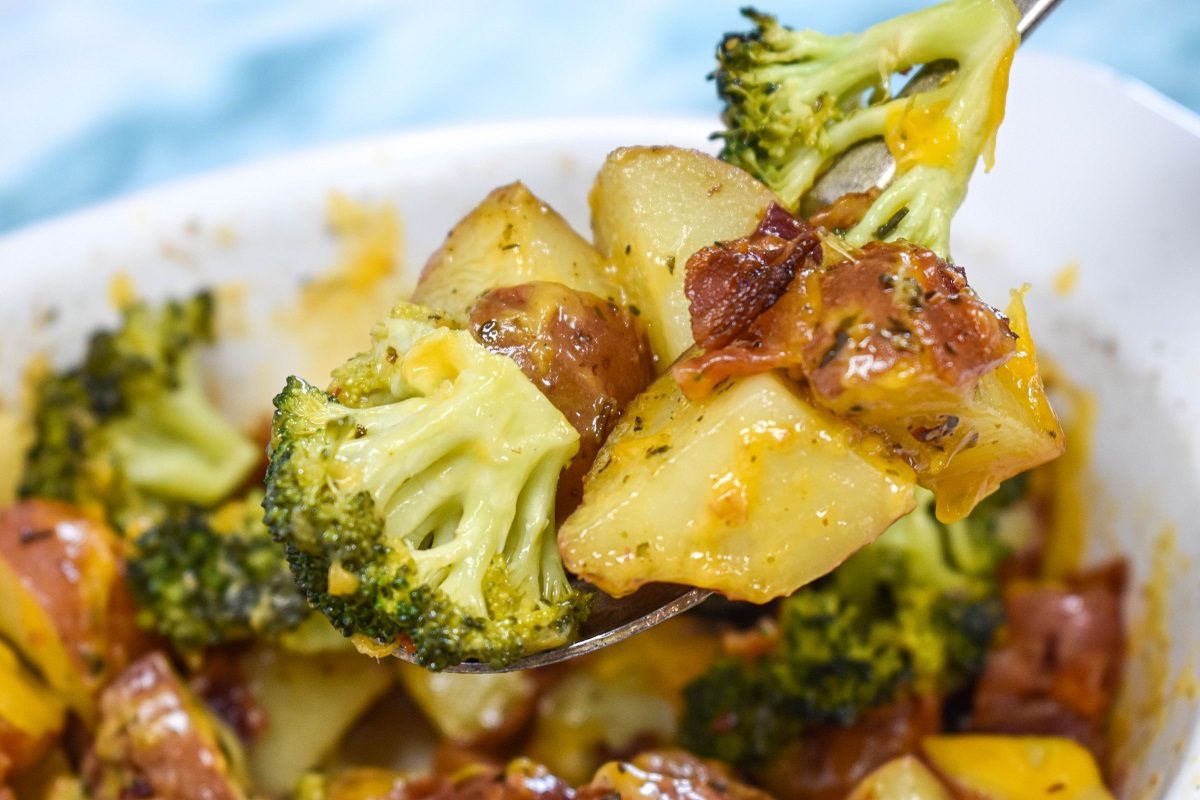 A scoopful of the potato broccoli bake held over the baking dish.