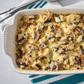 The reuben casserole in a white dish set on a teal and white striped kitchen towel.