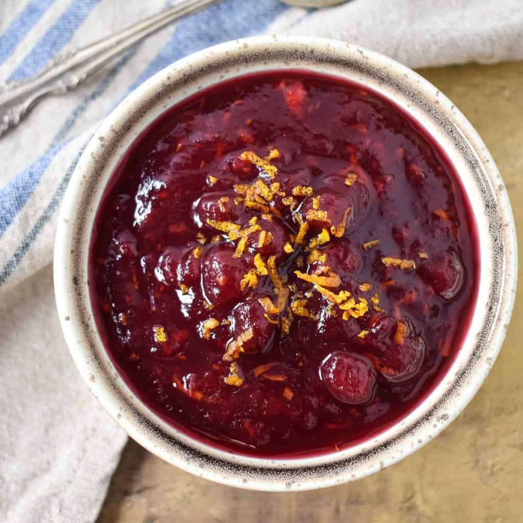 Cranberry orange sauce served in a small bowl and garnished with orange zest.