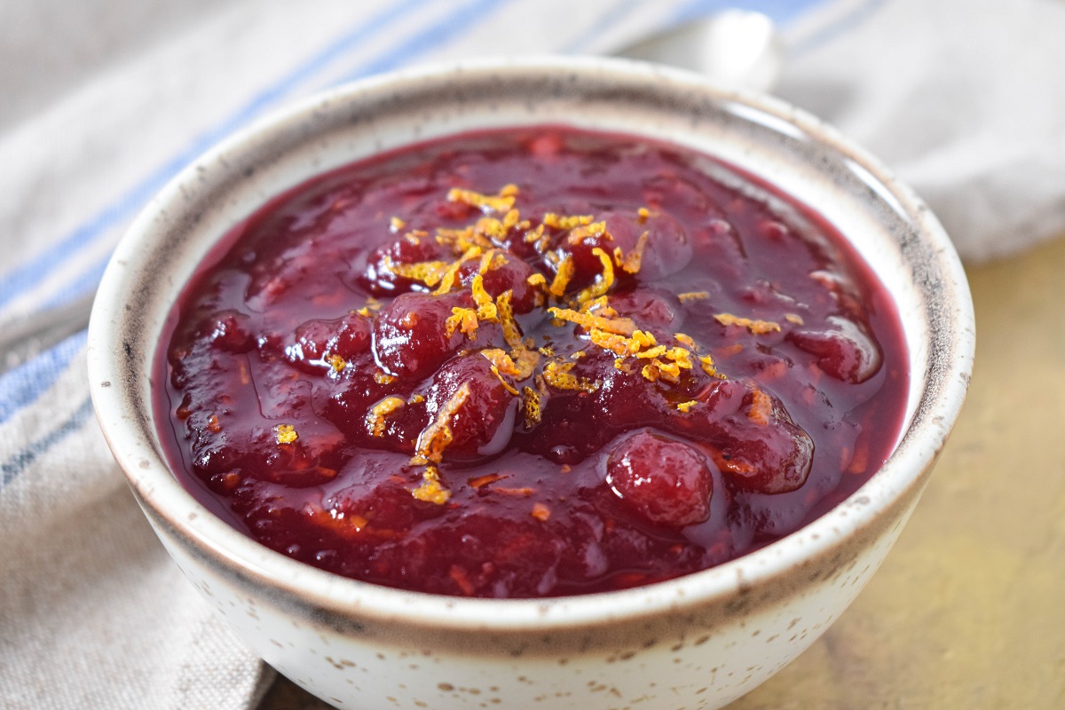 The cranberry orange sauce garnished with orange zest and served in a small beige bowl.