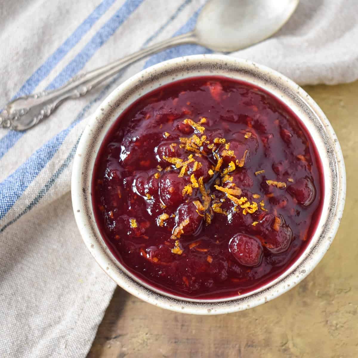 The cranberry orange sauce garnished with orange zest and served in a small beige bowl.