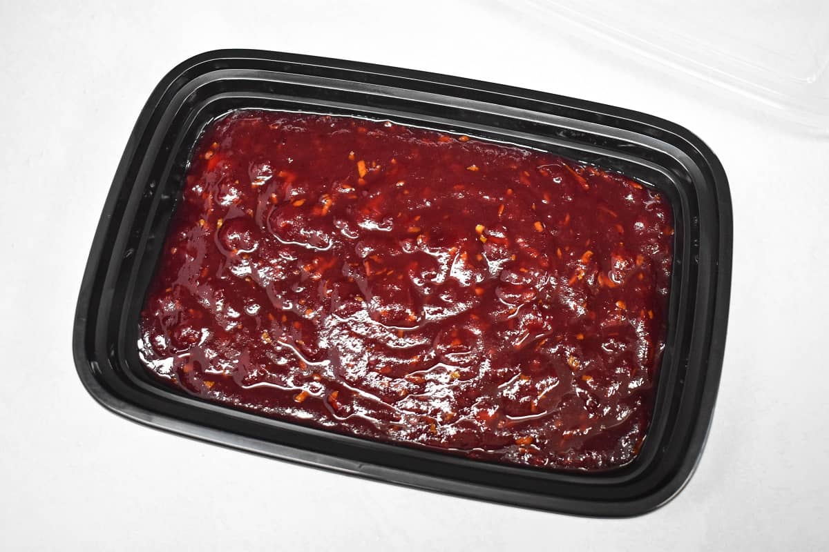 The finished sauce in a black container set on a white table.