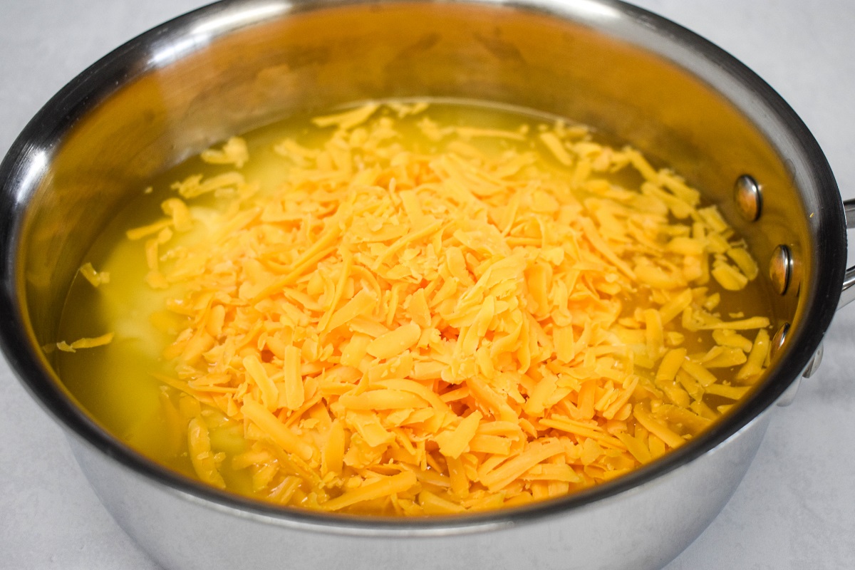 The cream of chicken, broth, and shredded cheese in a saucepan before cooking.