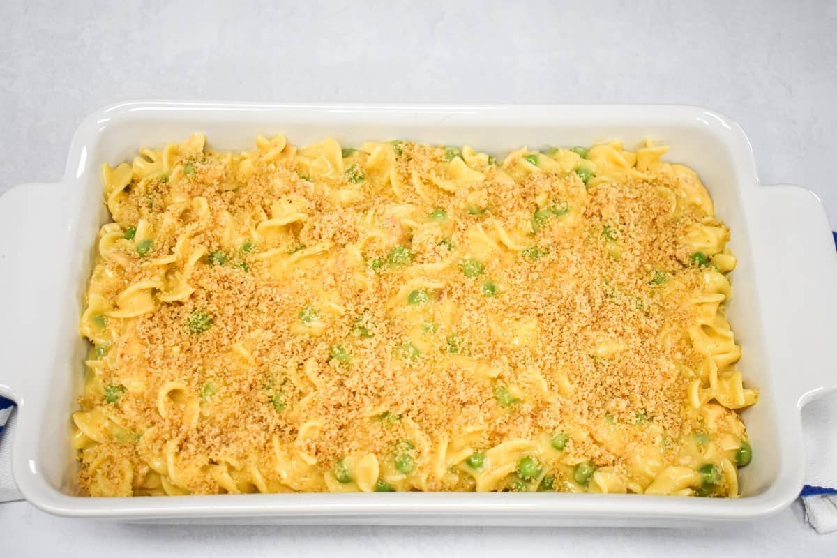 The prepared mixture topped with the breadcrumbs in a white baking dish set on a white table.